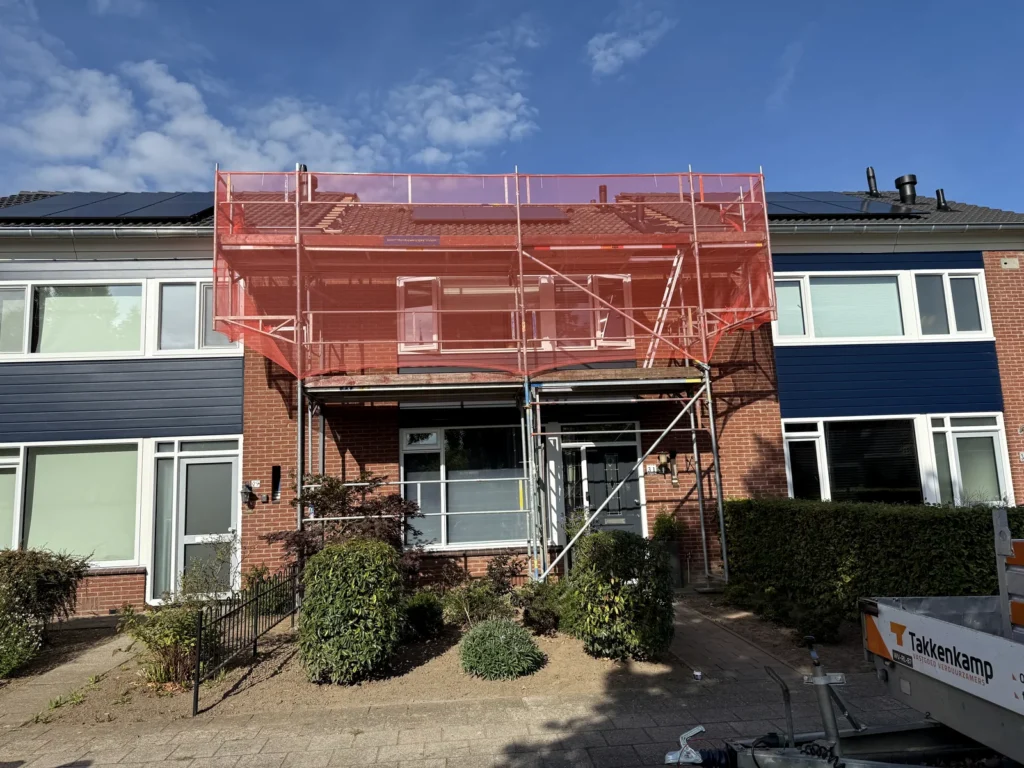 Woningproject met gevelsteiger en rood steigernet